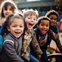 Auf dem Bild sind sechs fröhliche Kinder zu sehen, die eng beieinander stehen und in die Kamera lächeln. Sie befinden sich auf einem Spielplatz im Freien. Die Kinder tragen verschiedene farbenfrohe Kleidung. Im Hintergrund ist eine Holzkonstruktion zu erkennen. 