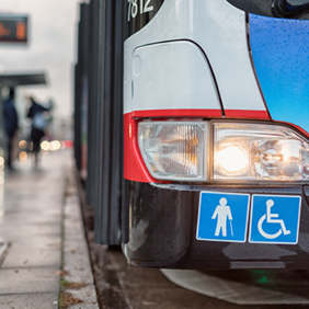 Auf dem Bild hält grade ein Bus des ÖPNV an einer Bushaltestellt. Abgebildert sich die Symbole für Senioren und Rollstuhlfahrer.