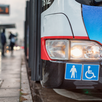 Auf dem Bild hält grade ein Bus des ÖPNV an einer Bushaltestellt. Abgebildert sich die Symbole für Senioren und Rollstuhlfahrer.