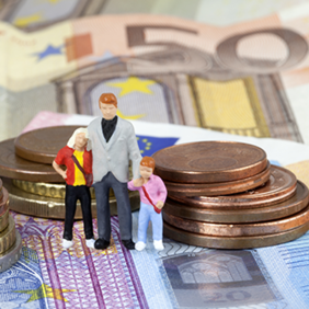 Das Bild zeigt drei Miniaturfiguren, die eine Familie darstellen, bestehend aus einem Erwachsenen und zwei Kindern. Sie stehen auf einem Haufen von Euro-Münzen und -Scheinen. Die Münzen sind in verschiedenen Größen gestapelt, und die Scheine sind im Hintergrund sichtbar.