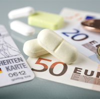Auf dem Bild sind eine Krankenversicherungskarte, mehrere Euro-Banknoten und -Münzen sowie einige Tabletten zu sehen. Die Krankenversicherungskarte liegt links im Vordergrund, während die Banknoten und Münzen rechts daneben platziert sind. Die Tabletten befinden sich in der Mitte des Bildes.