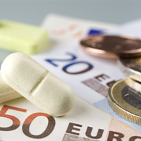 Auf dem Bild sind eine Krankenversicherungskarte, mehrere Euro-Banknoten und -Münzen sowie einige Tabletten zu sehen. Die Krankenversicherungskarte liegt links im Vordergrund, während die Banknoten und Münzen rechts daneben platziert sind. Die Tabletten befinden sich in der Mitte des Bildes.