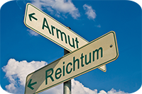 Das Bild zeigt zwei Straßenschilder, die in entgegengesetzte Richtungen zeigen. Auf dem Schild, das nach links weist, steht das Wort "Armut" und auf dem Schild, das nach rechts weist, steht das Wort "Reichtum". Der Himmel im Hintergrund ist blau mit einigen weißen Wolken.