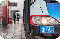 Auf dem Bild hält grade ein Bus des ÖPNV an einer Bushaltestellt. Abgebildert sich die Symbole für Senioren und Rollstuhlfahrer.